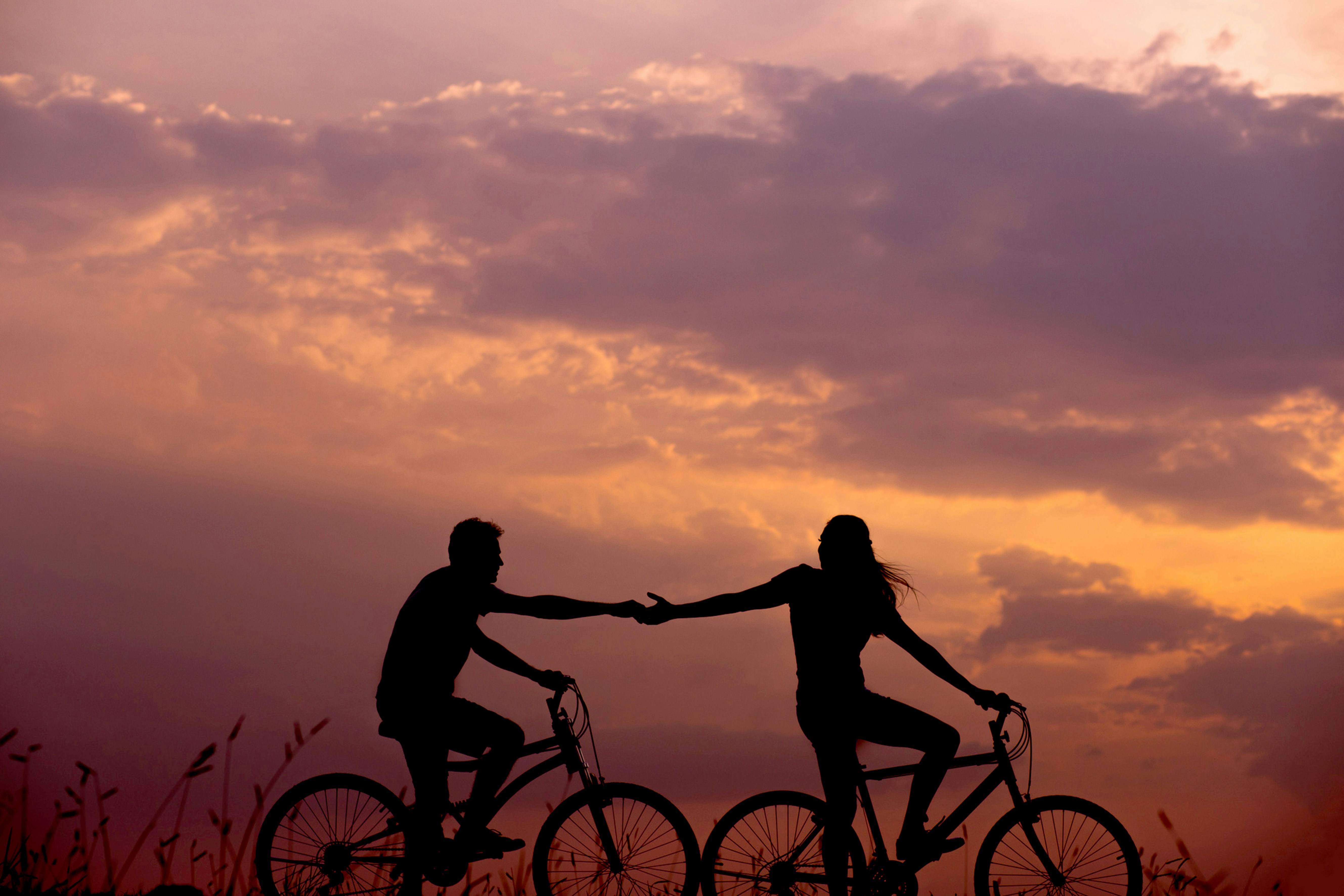 Casal de bicicleta ao pôr do sol